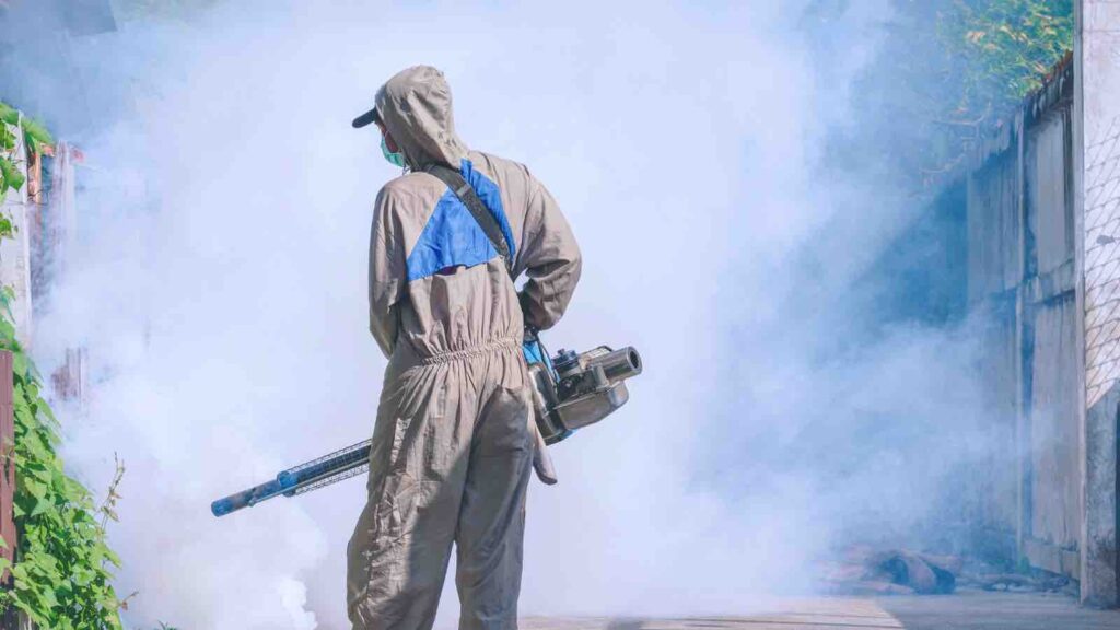 Healthcare worker using fogging machine spraying chemical to eliminate mosquitoes and prevent dengue fever in public community area by ภาพของPrapat Aowsakorn