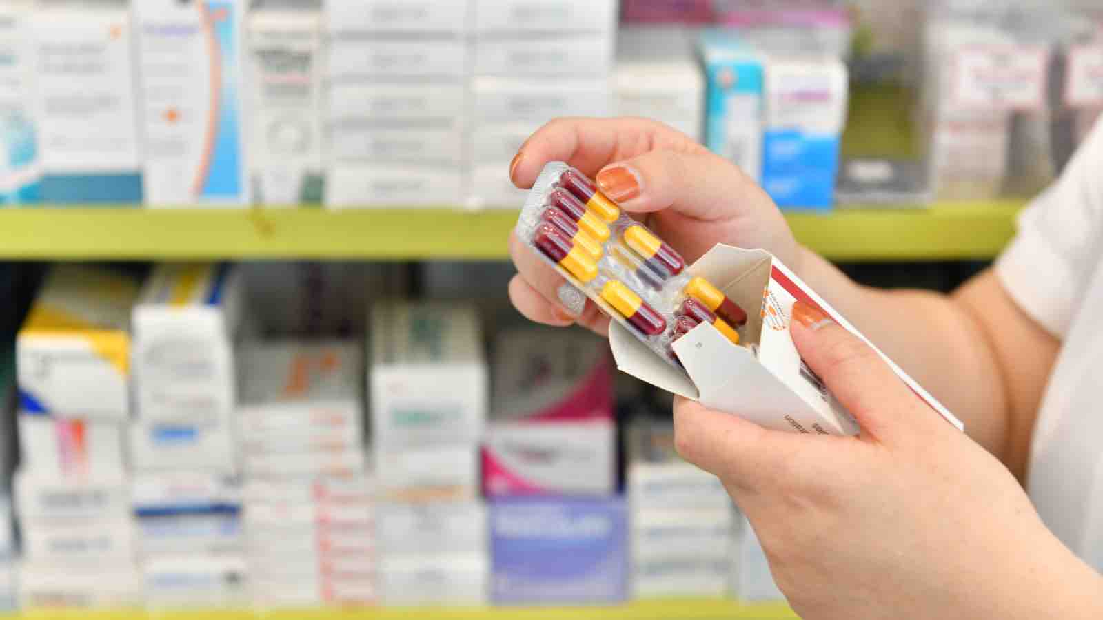 Hand holding medicine capsule pack in drugstore by MJ_Prototype from Getty Images