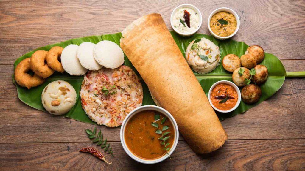 Group of South Indian food like Masala Dosa, Uttapam, Idli/idly, Wada/vada, sambar, appam, semolina halwa, upma served over banana leaf with colourful chutneys, selective focus by Arundhati Sathe from Getty Images