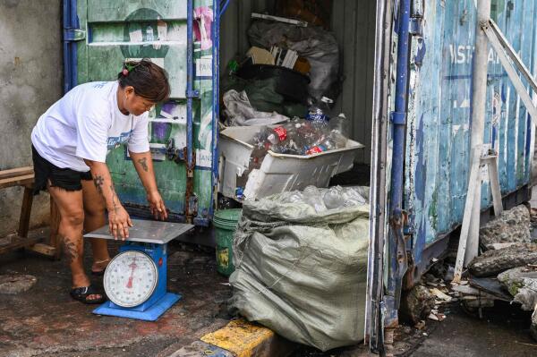 Marita Blanco, who buys plastic bottles, styrofoam and candy wrappers for two pesos (3.4 US cents) a kilogramme to be resold at a 25 per cent markup to US charity Friends of Hope in its waste-to-cash programme, handling her weighing machine by a shipping container in Manila. – AFP